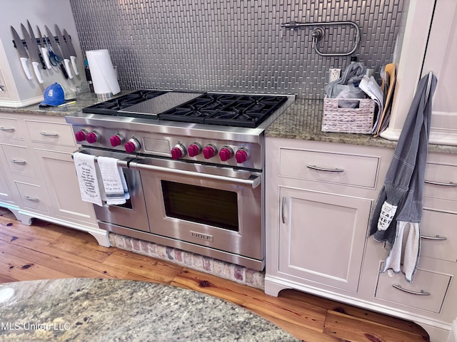 236 Sawbridge Dr, Ridgeland, MS 39157 - kitchen featuring range with two ovens, white cabinets, light wood-style floors, tasteful backsplash, and light stone counters