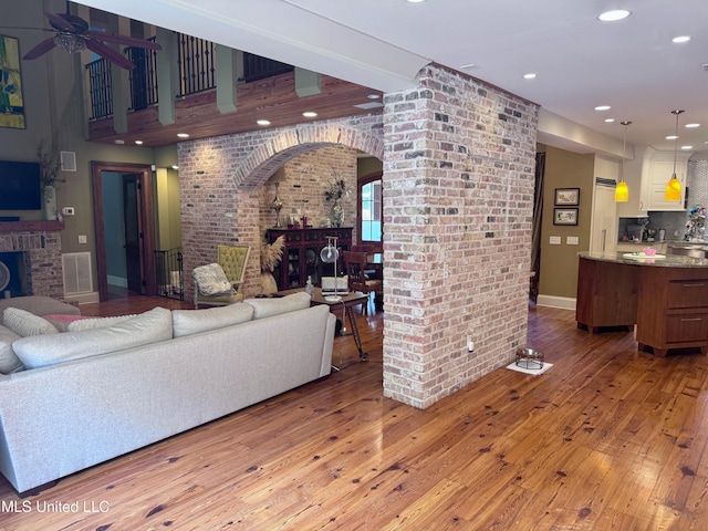 236 Sawbridge Dr, Ridgeland, MS 39157 - living area featuring arched walkways, a ceiling fan, wood-type flooring, a fireplace, and brick wall