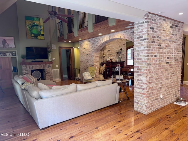 236 Sawbridge Dr, Ridgeland, MS 39157 - living room featuring a brick fireplace, arched walkways, ceiling fan, wood finished floors, and brick wall