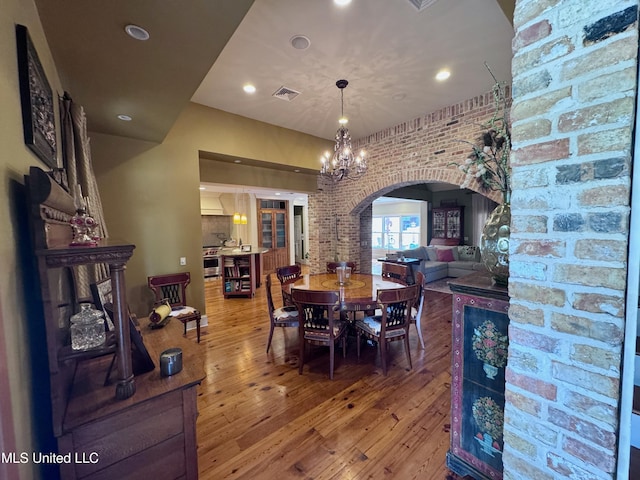 236 Sawbridge Dr, Ridgeland, MS 39157 - dining area featuring arched walkways, brick wall, wood-type flooring, a chandelier, and recessed lighting