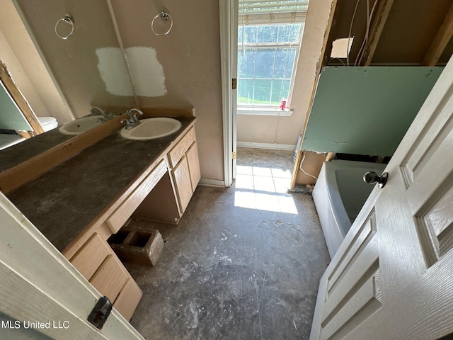 bathroom with vanity, a tub, and concrete floors