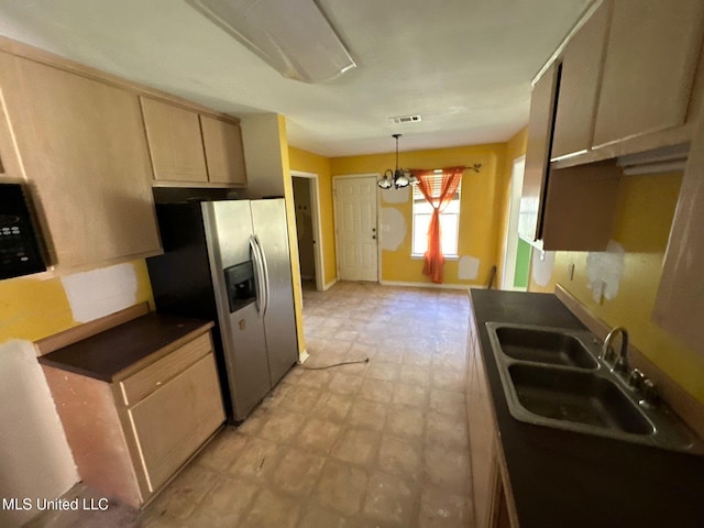 kitchen with stainless steel fridge, an inviting chandelier, light brown cabinetry, pendant lighting, and sink