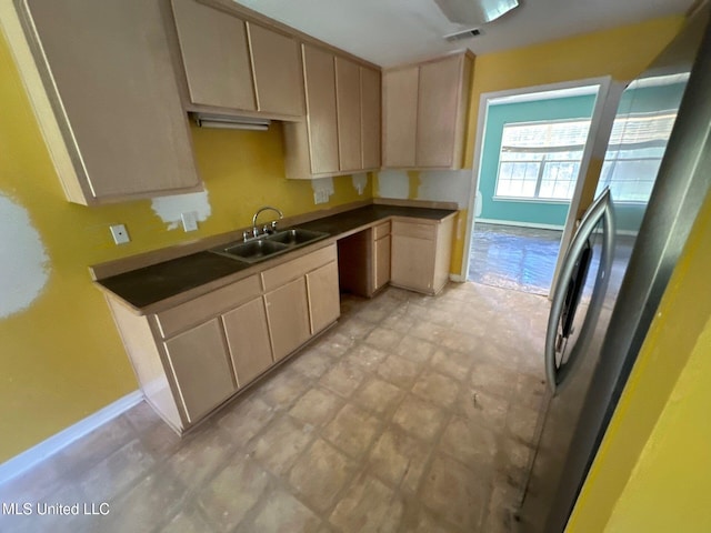 kitchen with light brown cabinetry, sink, and stainless steel refrigerator