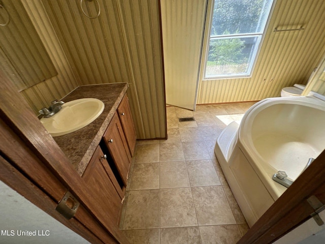 bathroom featuring vanity, a tub to relax in, tile patterned flooring, and toilet