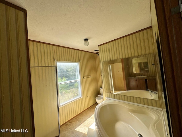 bathroom with ornamental molding, a tub, a textured ceiling, and toilet