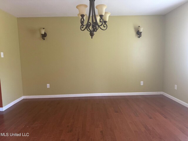 3820 Beamon Rd, Kosciusko, MS 39090 - empty room with dark wood-style floors, a notable chandelier, and baseboards