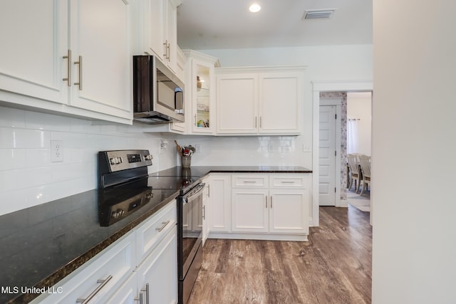 kitchen with visible vents, backsplash, stainless steel appliances, wood finished floors, and white cabinetry