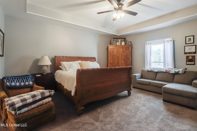 carpeted bedroom with a tray ceiling and a ceiling fan