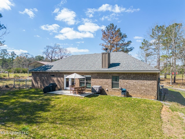 rear view of house featuring fence, roof with shingles, a lawn, a patio area, and brick siding