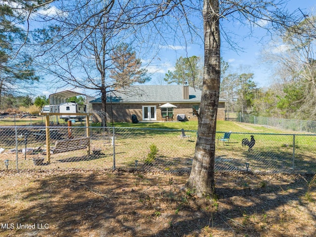 exterior space featuring a lawn, a detached carport, a chimney, and fence