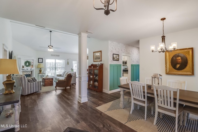 dining area featuring ceiling fan with notable chandelier, wood finished floors, wallpapered walls, decorative columns, and lofted ceiling