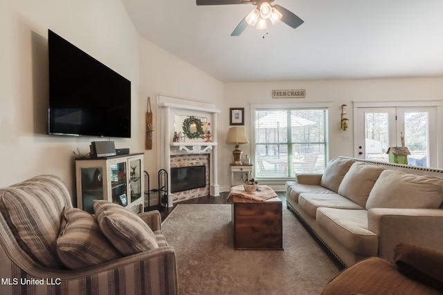 living room with a tiled fireplace, lofted ceiling, wood finished floors, and ceiling fan