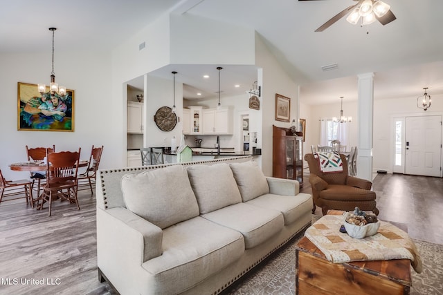 living area featuring recessed lighting, decorative columns, wood finished floors, and ceiling fan with notable chandelier