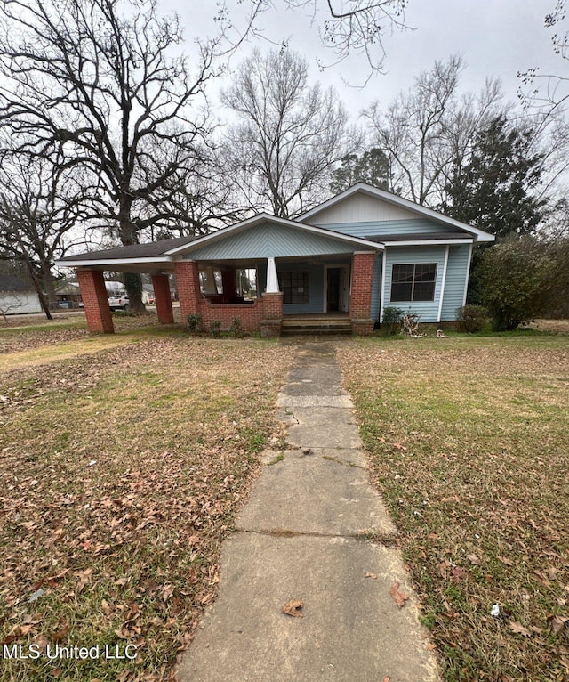 view of front facade featuring brick siding, a porch, a carport, and a front yard