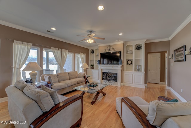 living room with light wood-type flooring, ceiling fan, and ornamental molding