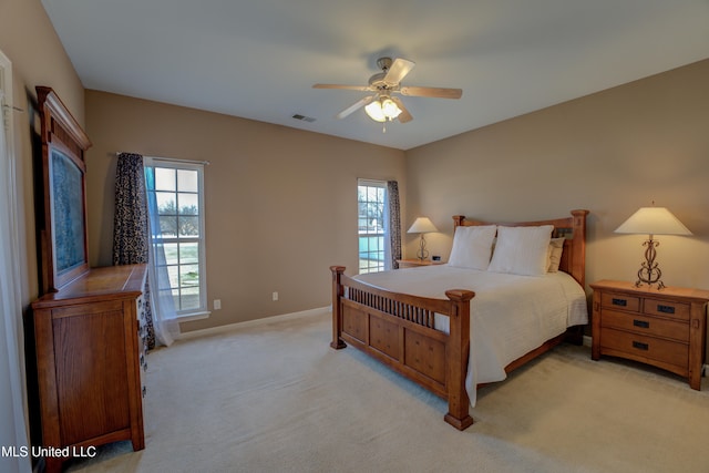 bedroom with light colored carpet, multiple windows, and ceiling fan