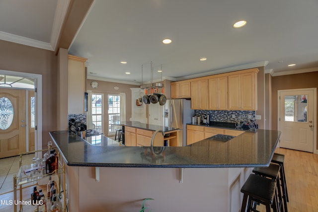 kitchen featuring a breakfast bar area, kitchen peninsula, stainless steel fridge, and light hardwood / wood-style flooring