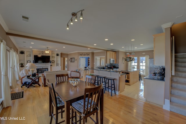 dining space featuring french doors, light hardwood / wood-style floors, built in features, and crown molding