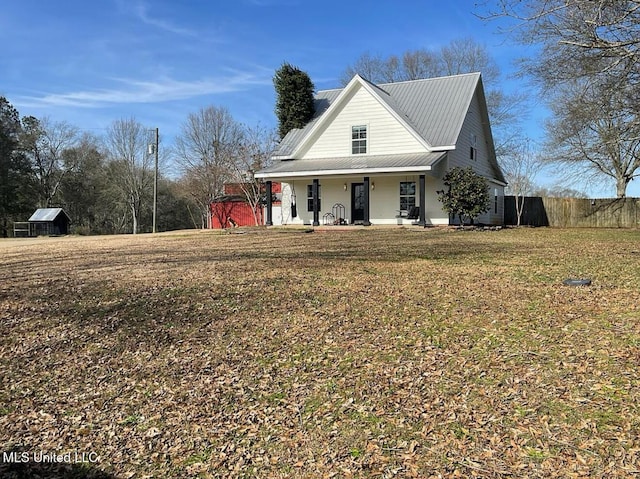 view of front of house featuring a front lawn, fence, covered porch, and metal roof