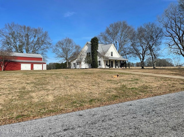 view of home's exterior featuring an outbuilding, driveway, a detached garage, and a yard