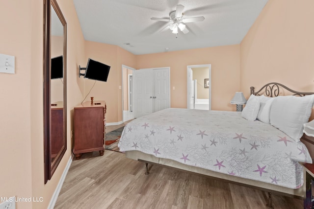 bedroom featuring connected bathroom, a closet, light hardwood / wood-style flooring, a textured ceiling, and ceiling fan