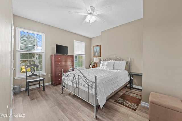 bedroom with ceiling fan, a textured ceiling, and light hardwood / wood-style flooring