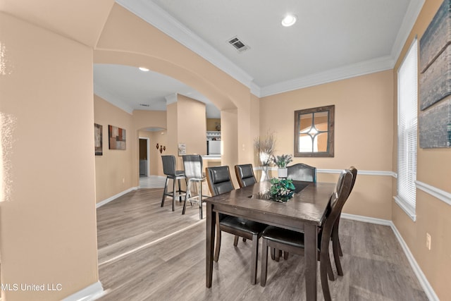 dining space with light hardwood / wood-style floors and crown molding