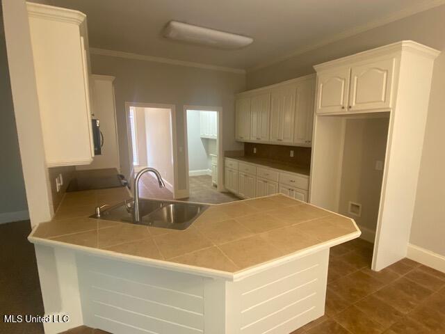 309 Barrington Cv, Byram, MS 39272 - kitchen with a peninsula, white cabinets, tile countertops, and crown molding