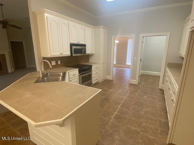 309 Barrington Cv, Byram, MS 39272 - kitchen featuring stainless steel appliances, a peninsula, ornamental molding, ceiling fan, and white cabinetry