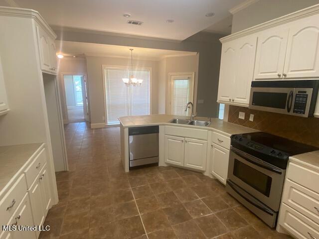 309 Barrington Cv, Byram, MS 39272 - kitchen with appliances with stainless steel finishes, a chandelier, a peninsula, white cabinetry, and light countertops