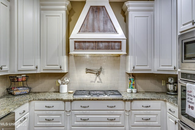 kitchen with decorative backsplash, white cabinets, and appliances with stainless steel finishes