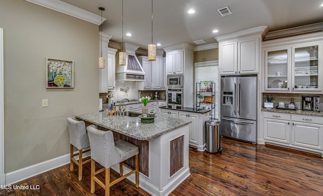 kitchen with custom exhaust hood, backsplash, white cabinets, dark stone countertops, and appliances with stainless steel finishes