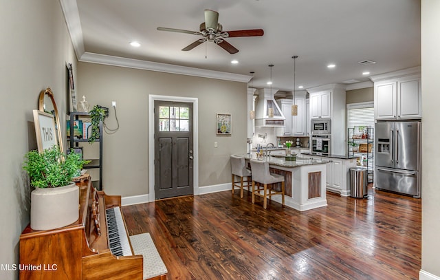 kitchen with white cabinetry, hanging light fixtures, a kitchen breakfast bar, light stone counters, and appliances with stainless steel finishes