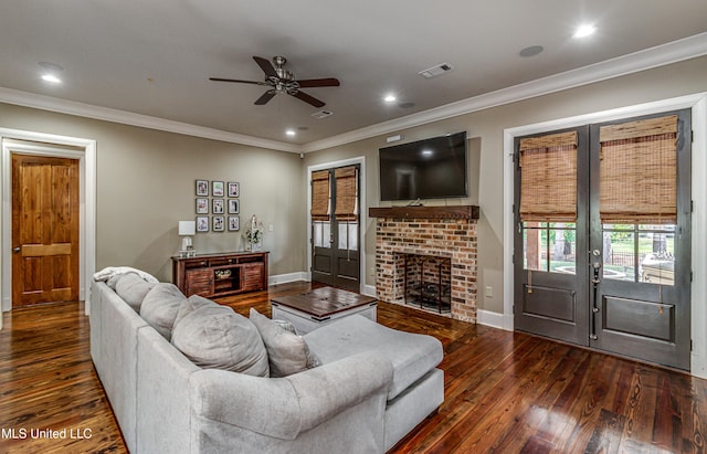 living room featuring crown molding, a fireplace, dark wood-type flooring, and french doors