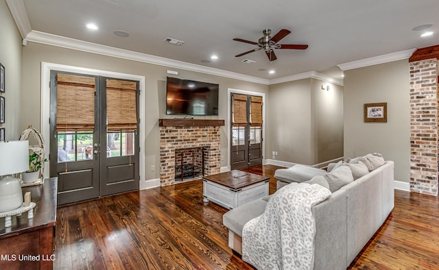 living room featuring a fireplace, ornamental molding, ceiling fan, and dark wood-type flooring