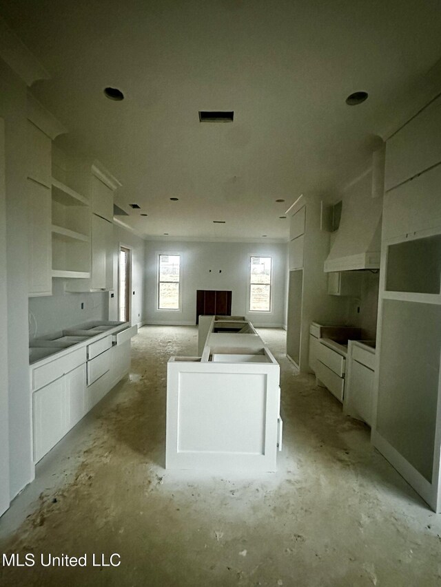 kitchen with cooktop, white cabinetry, and range hood