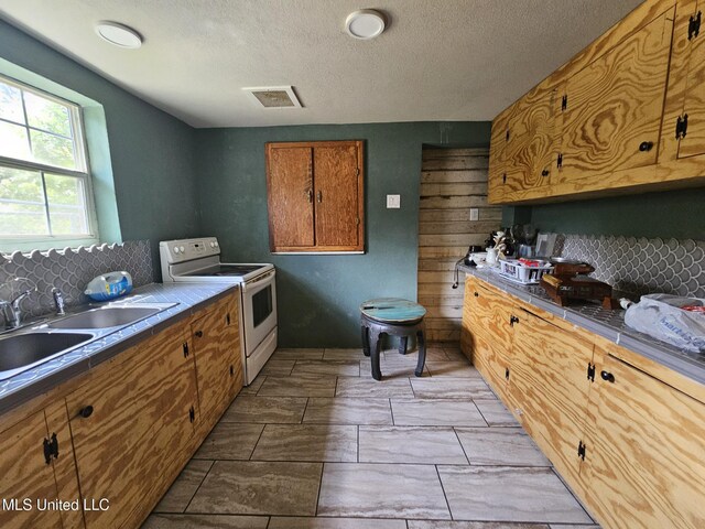633 24th St, Gulfport, MS 39501 - kitchen featuring electric range, decorative backsplash, brown cabinets, and a textured ceiling