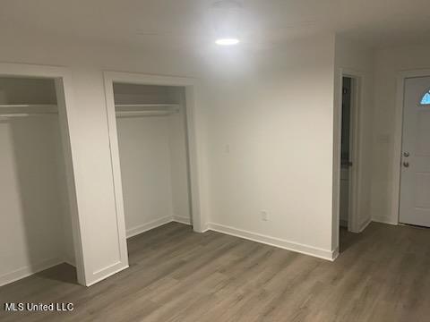 unfurnished bedroom featuring multiple closets and dark hardwood / wood-style flooring