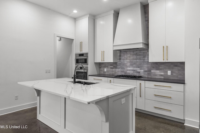 kitchen featuring white cabinets, light stone counters, appliances with stainless steel finishes, wall chimney range hood, and backsplash