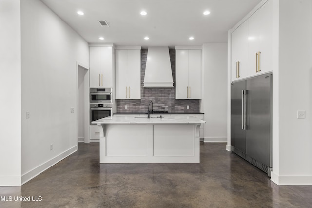 kitchen with stainless steel appliances, a sink, visible vents, wall chimney range hood, and backsplash