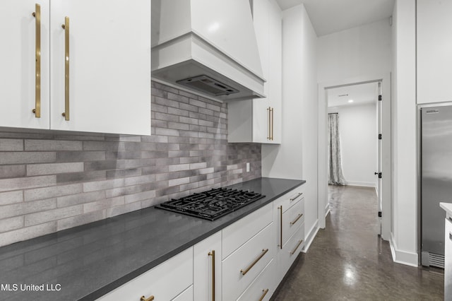 kitchen featuring custom exhaust hood, black gas cooktop, dark countertops, tasteful backsplash, and white cabinets