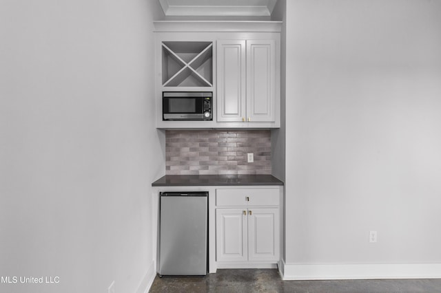 bar featuring appliances with stainless steel finishes, concrete floors, baseboards, and tasteful backsplash