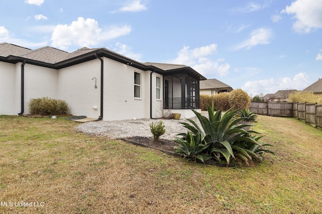 exterior space featuring brick siding, a lawn, and fence