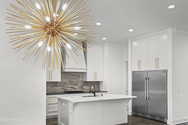 kitchen featuring decorative backsplash, white cabinets, a sink, and built in refrigerator