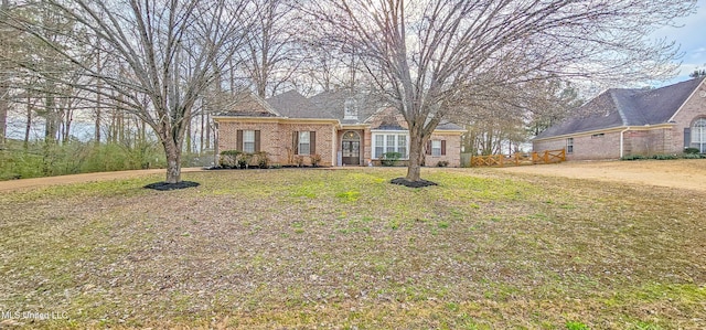 view of front of house featuring brick siding, fence, and a front yard