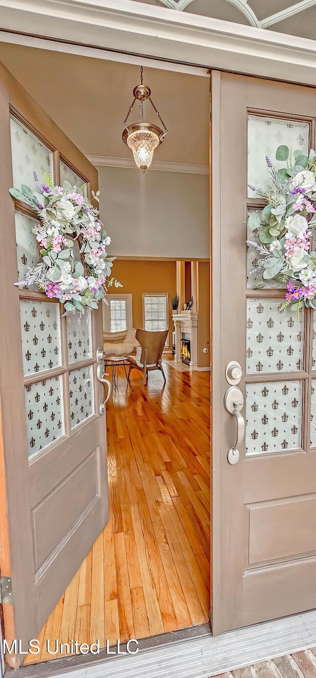 entryway featuring ornamental molding, a lit fireplace, and hardwood / wood-style floors