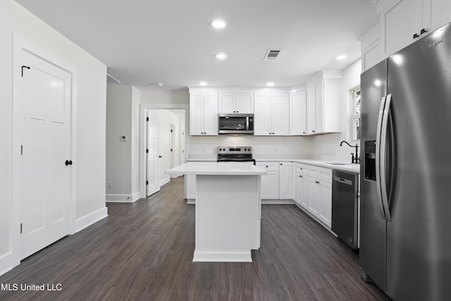 kitchen with dark wood-style floors, a sink, stainless steel appliances, light countertops, and white cabinets