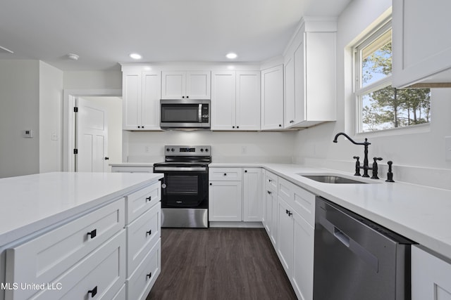 kitchen featuring dark wood finished floors, light countertops, stainless steel appliances, white cabinetry, and a sink