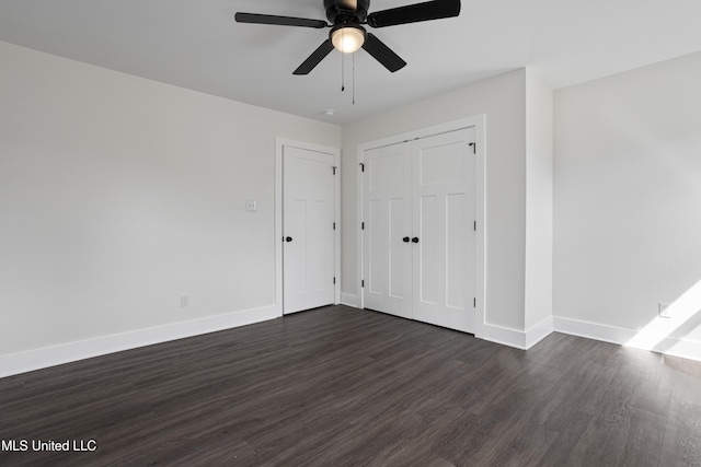 interior space with a closet, baseboards, dark wood-style flooring, and ceiling fan