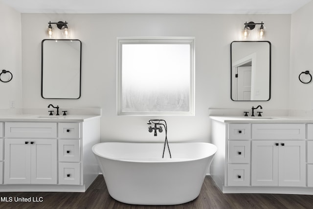 full bathroom with a soaking tub, a sink, and wood finished floors